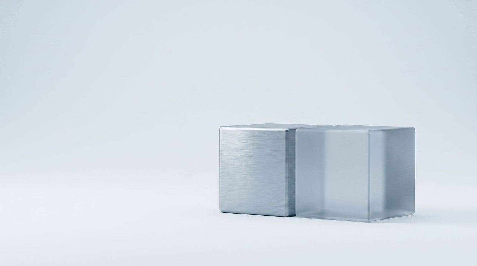 A solid steel cube beside an identical frosted glass cube