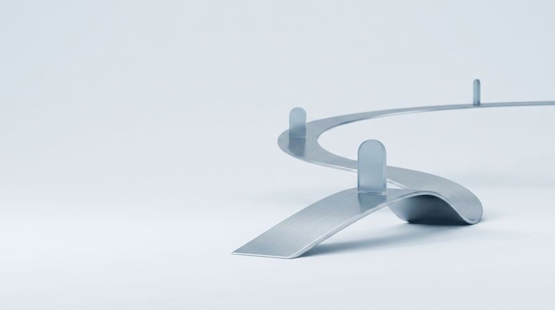 A steel ribbon curving into the distance with glass markers along its length