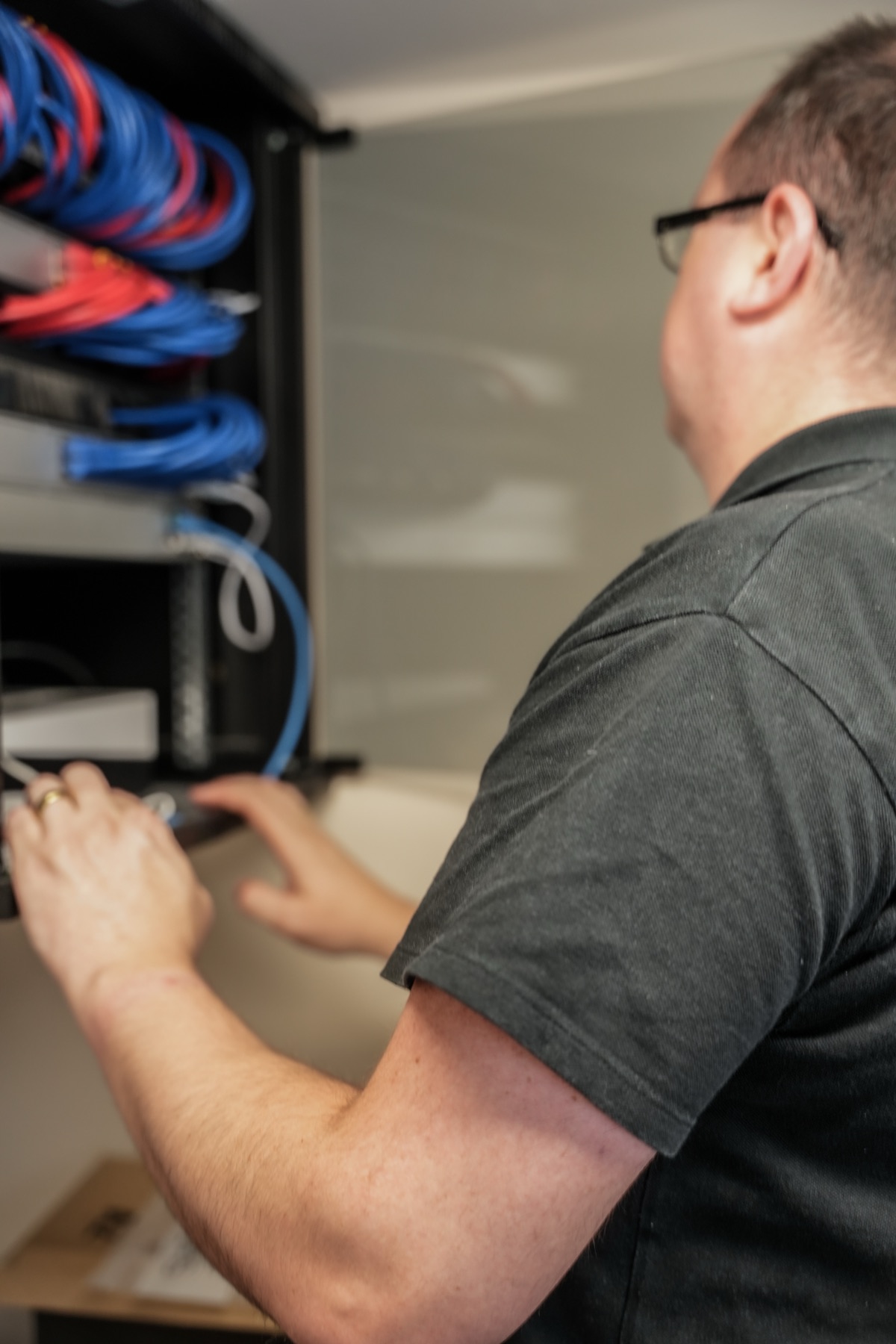 Panoptic engineer working on cabling at a comms cabinet during a network install